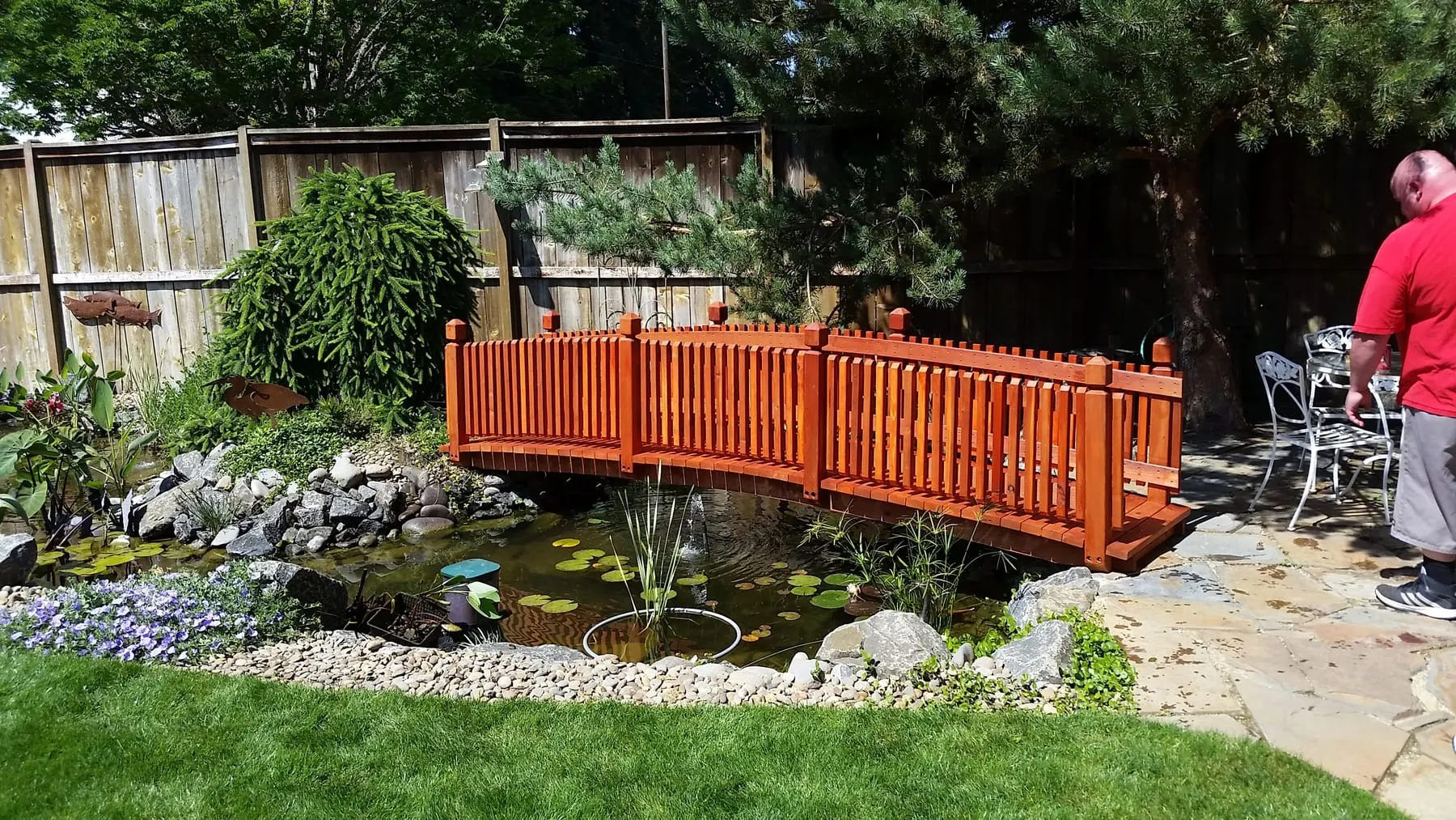 Custom-built redwood garden bridge over a lily pond with stone edging