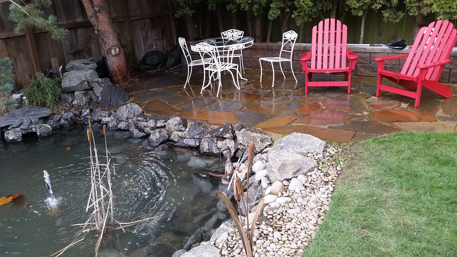Ornamental pond with pink Adirondack chairs and white patio furniture on deck
