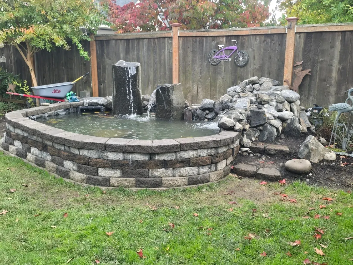 Backyard pond with stone edging, waterfall, and rock formation