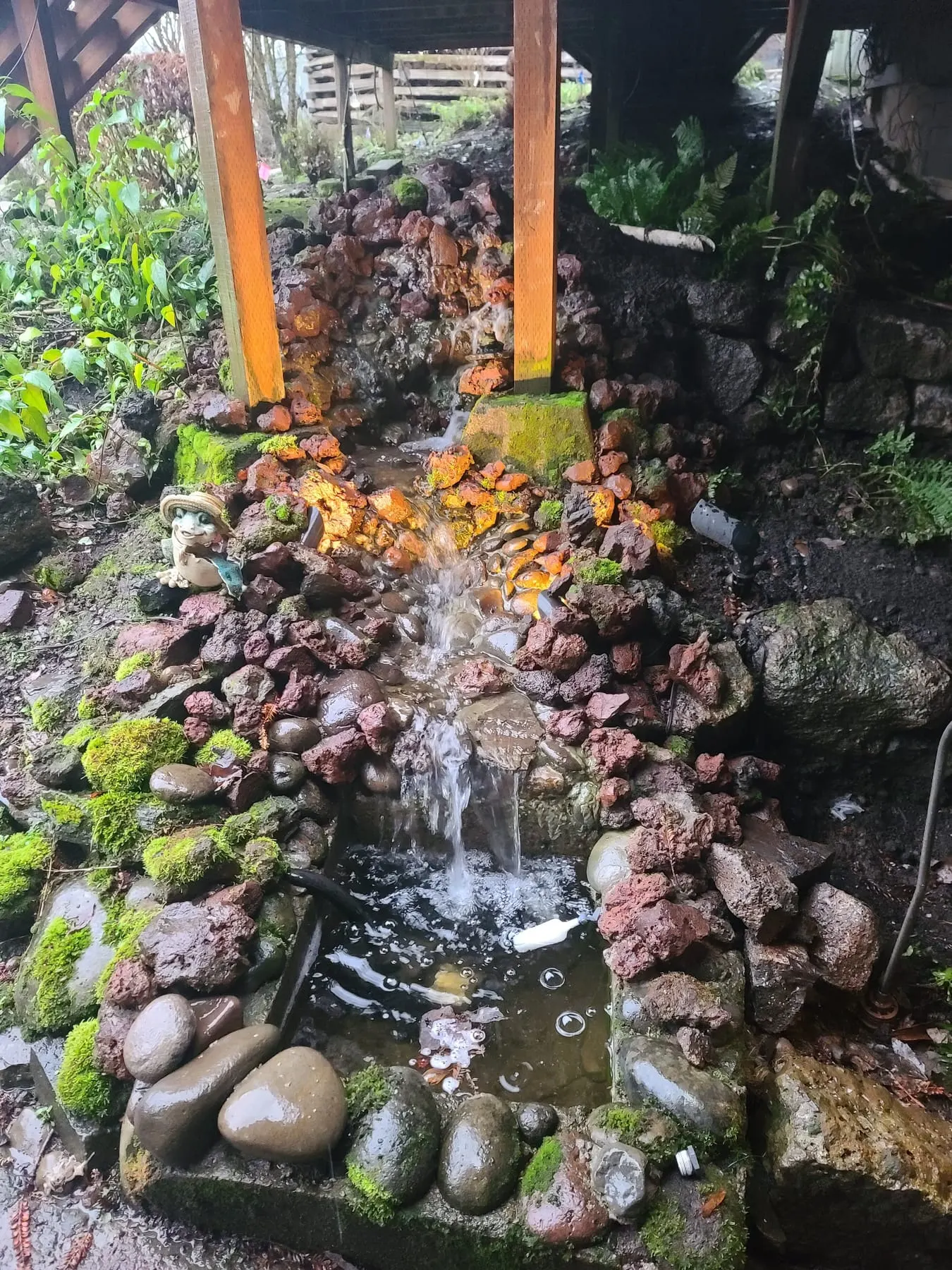 Waterfall cascading over stacked stones with moss and boulders